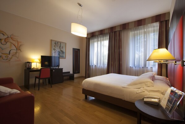 A hotel room with a bed, desk, chair, and a television.