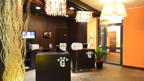 Un área de recepción con dos mostradores oscuros, un televisor y una planta decorativa.