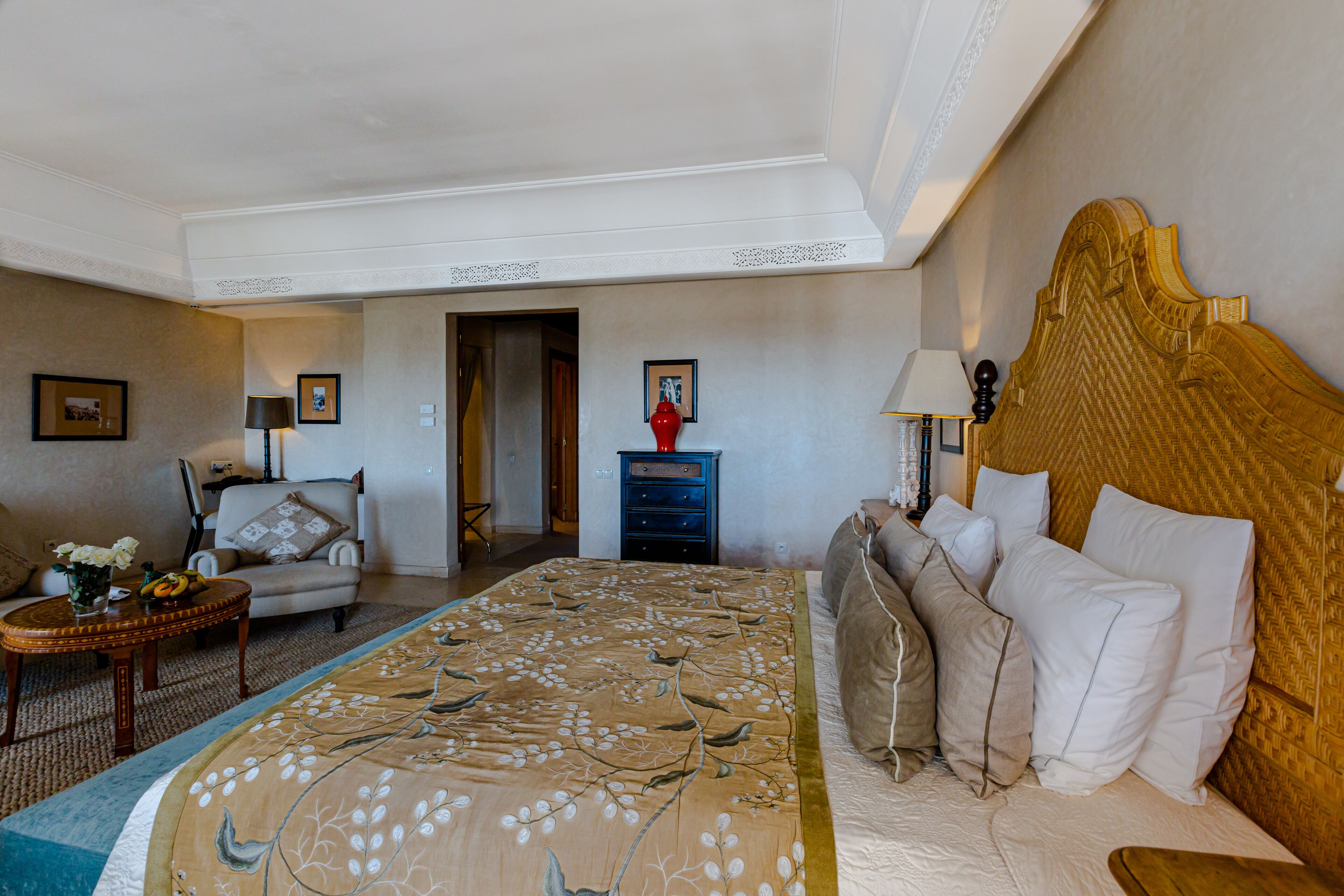 Habitación de hotel con una cama grande, un área de descanso con una silla y una mesita, y un aparador.