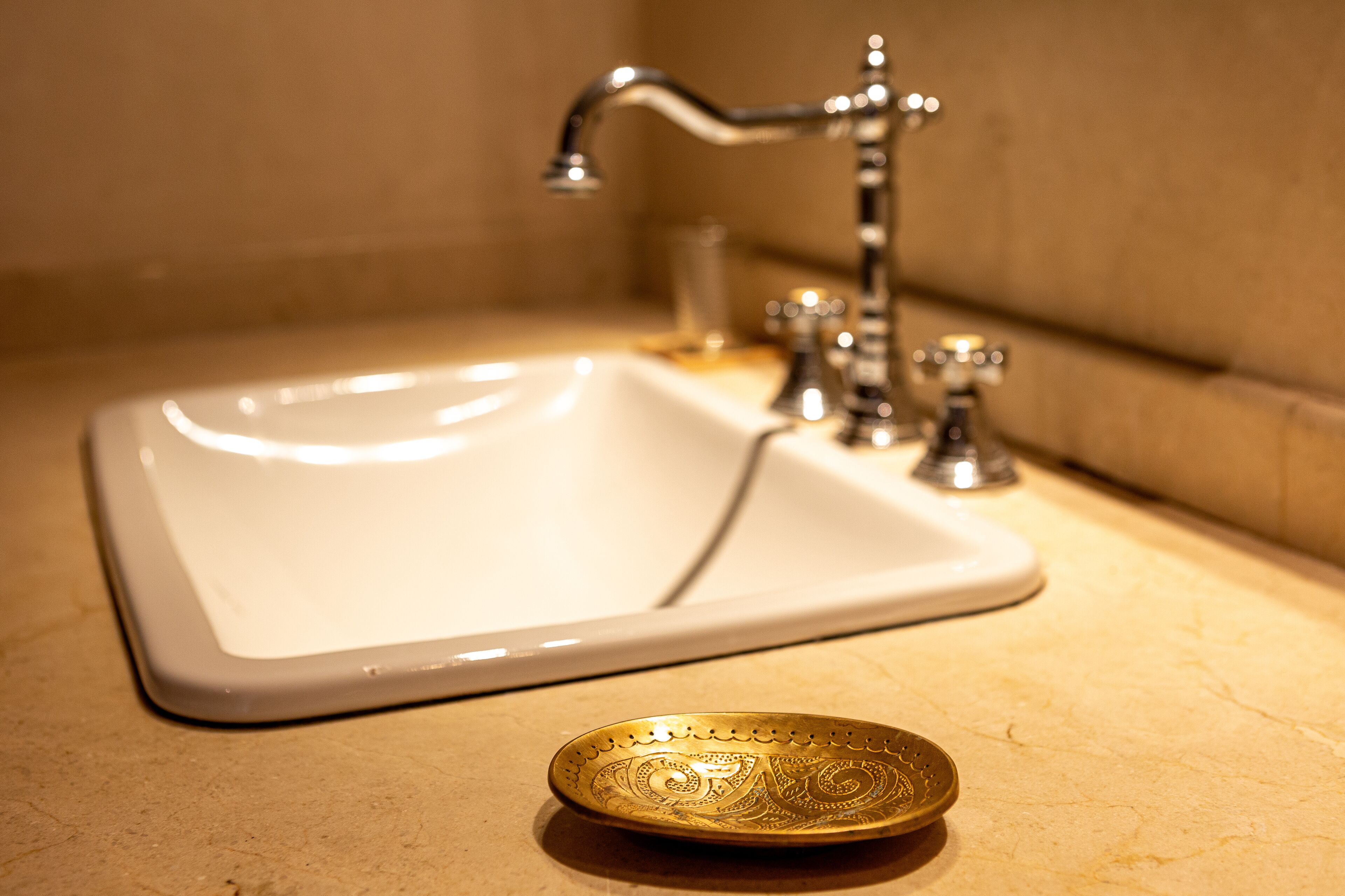 Un lavabo de salle de bain orné d’une plaque décorative dorée sur le plan de travail.
