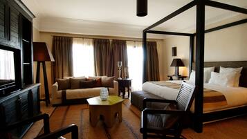 A four-poster bed, a sofa, a coffee table, and a TV in a hotel room.