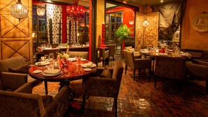 A restaurant with round tables set for dining, surrounded by upholstered chairs.