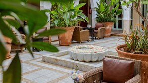 A courtyard with wicker furniture, potted plants, and a tiled floor.