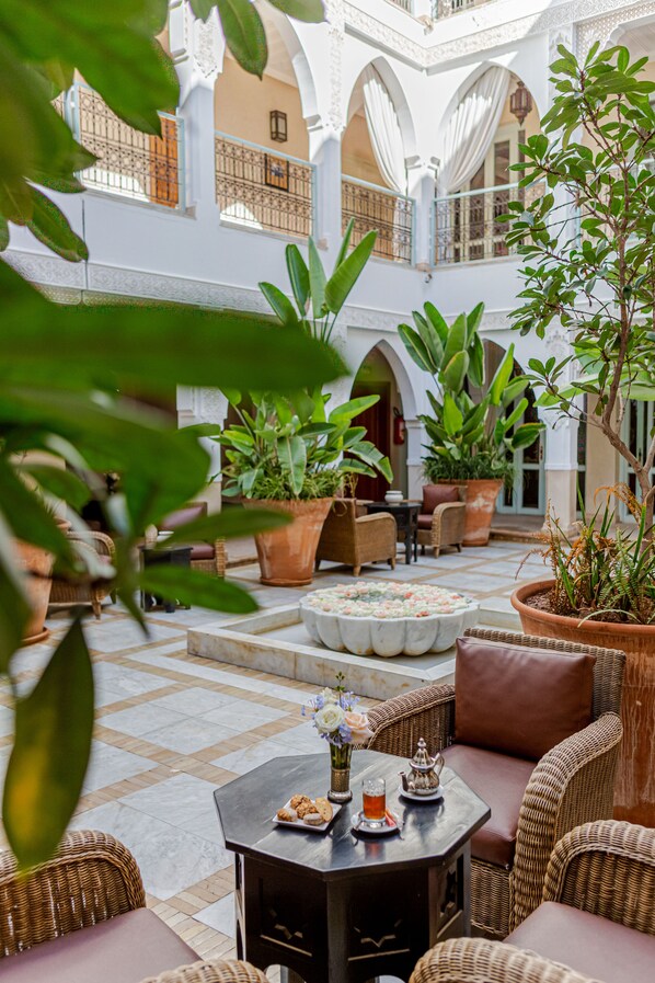 A courtyard with wicker furniture, potted plants, and a tiled floor. - Riad Villa Blanche (Agadir)