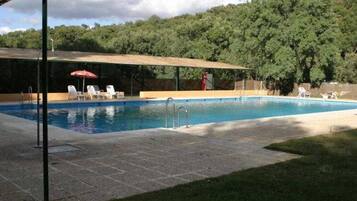 Een buitenzwembad, ligstoelen bij het zwembad