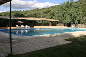 Una piscina al aire libre, sillones reclinables de piscina