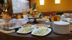 Una mesa de buffet con diversos alimentos, como frutas, pasteles y productos lácteos.