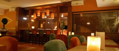 Un restaurante con muebles de madera, luces colgantes tipo lámpara y una zona de bar.