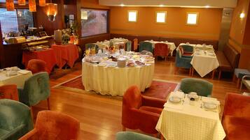 Uma sala de jantar com mesas redondas, cadeiras e um buffet.