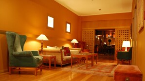 Un salón acogedor con un sillón verde, un sofá, una mesita y dos lámparas.