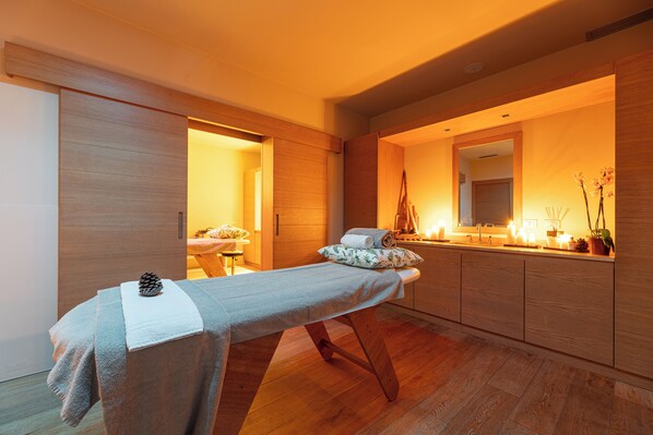 Um spa moderno com um banco de madeira, um espelho e um pequeno altar com velas e flores.