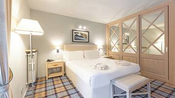 Ein Hotelzimmer mit Bett, Nachttischen, einer Bank, einem Schrank und einer Stehlampe.