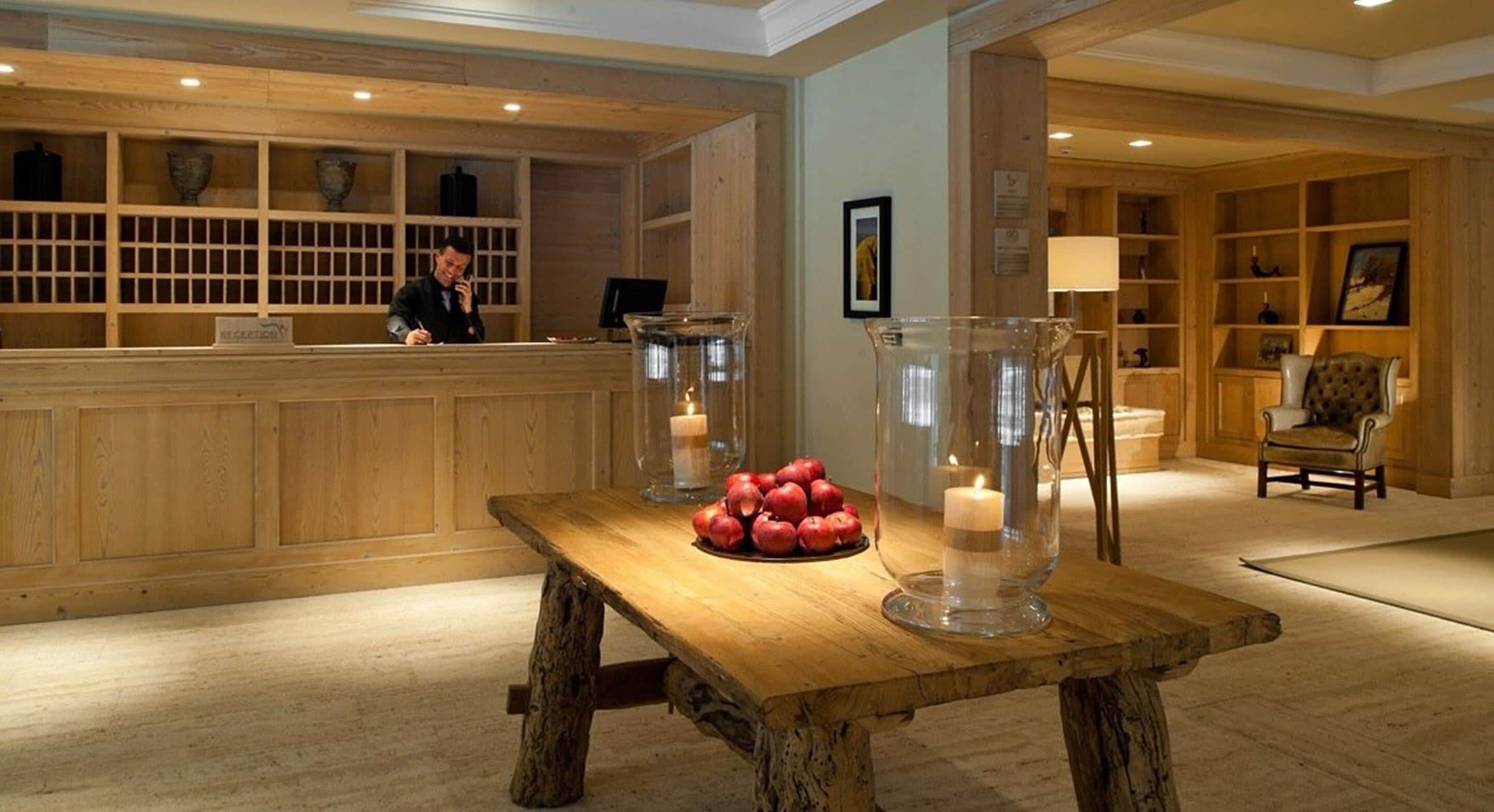 Un espace d’accueil comprenant un comptoir en bois, une table avec des pommes et des bougies, et une chaise.