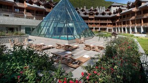 Um resort com estrutura em formato de pirâmide de vidro, varandas de madeira e área de piscina.