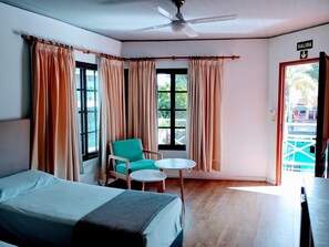A hotel room with a bed, a chair, a small table, a ceiling fan, and a view of the outside. - Guarumba Apart Hotel (Federacion)