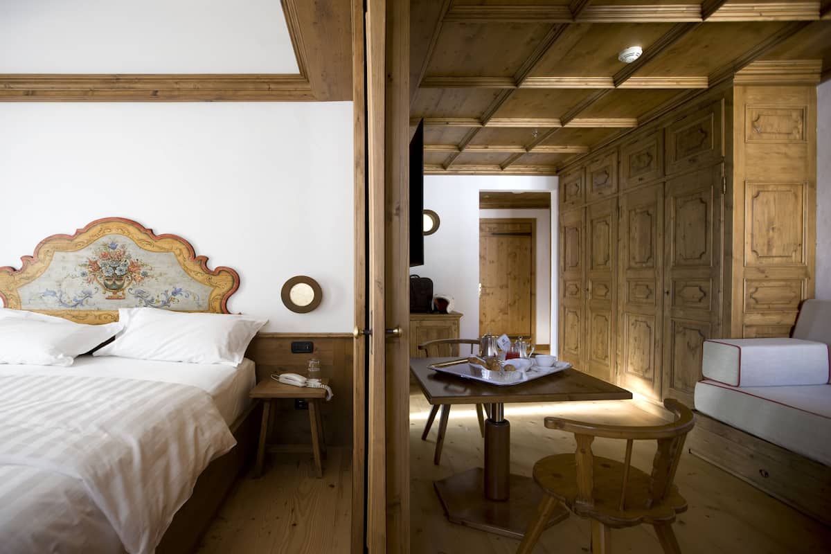 A bedroom with a wooden headboard, a bedside table with a lamp, and a wooden floor.
