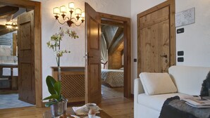 A cozy room with a wooden door, a white sofa, a table with breakfast items, and a potted orchid. - Cortina (Garda)