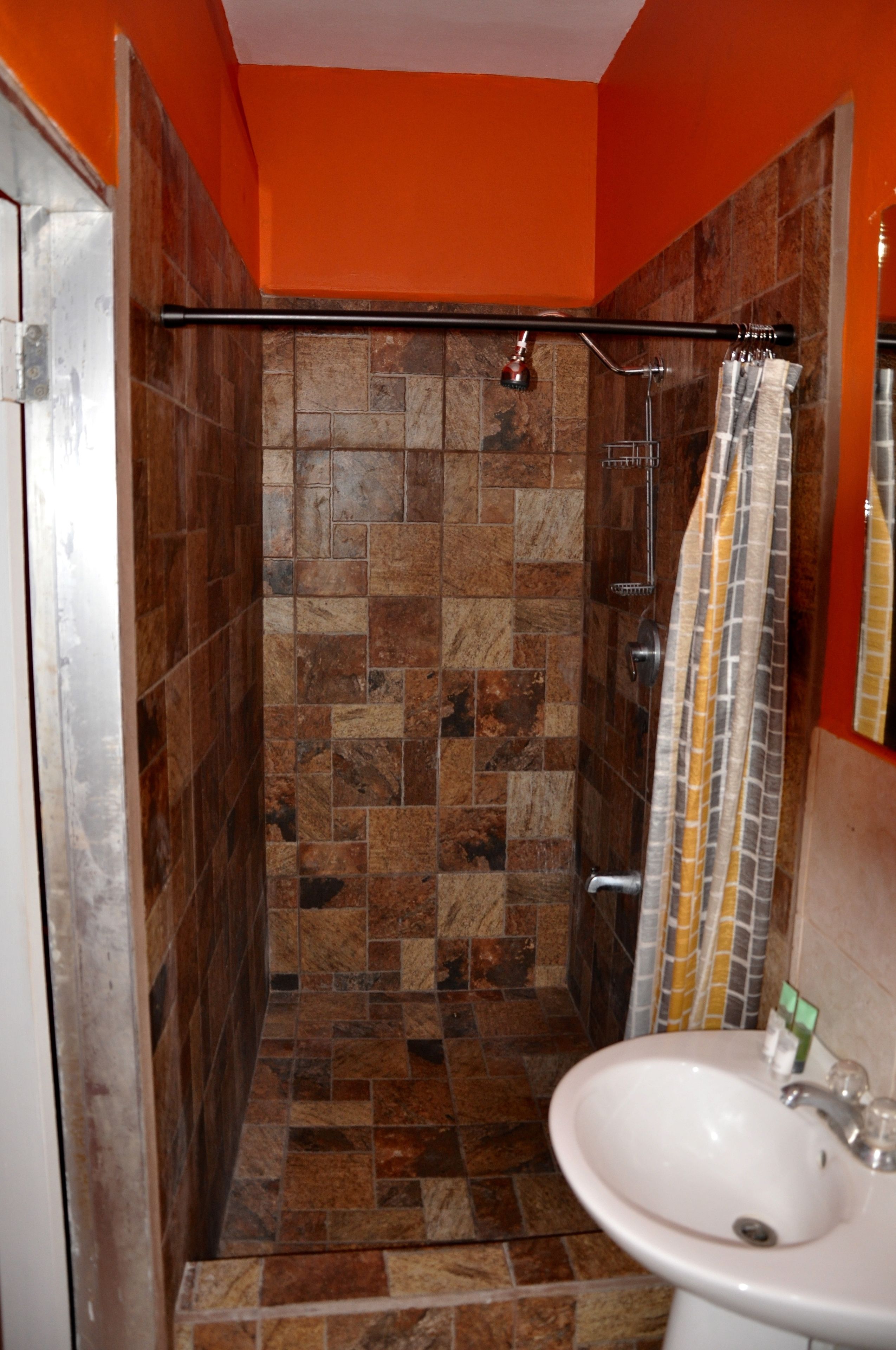 Un baño con ducha, paredes de azulejos y lavamanos.