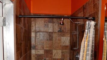 Un baño con ducha, paredes de azulejos y lavamanos.