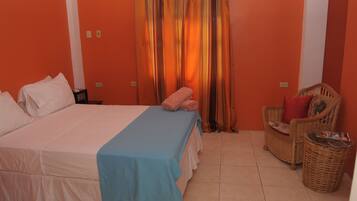 Una habitación con cama, una silla y una cortina.