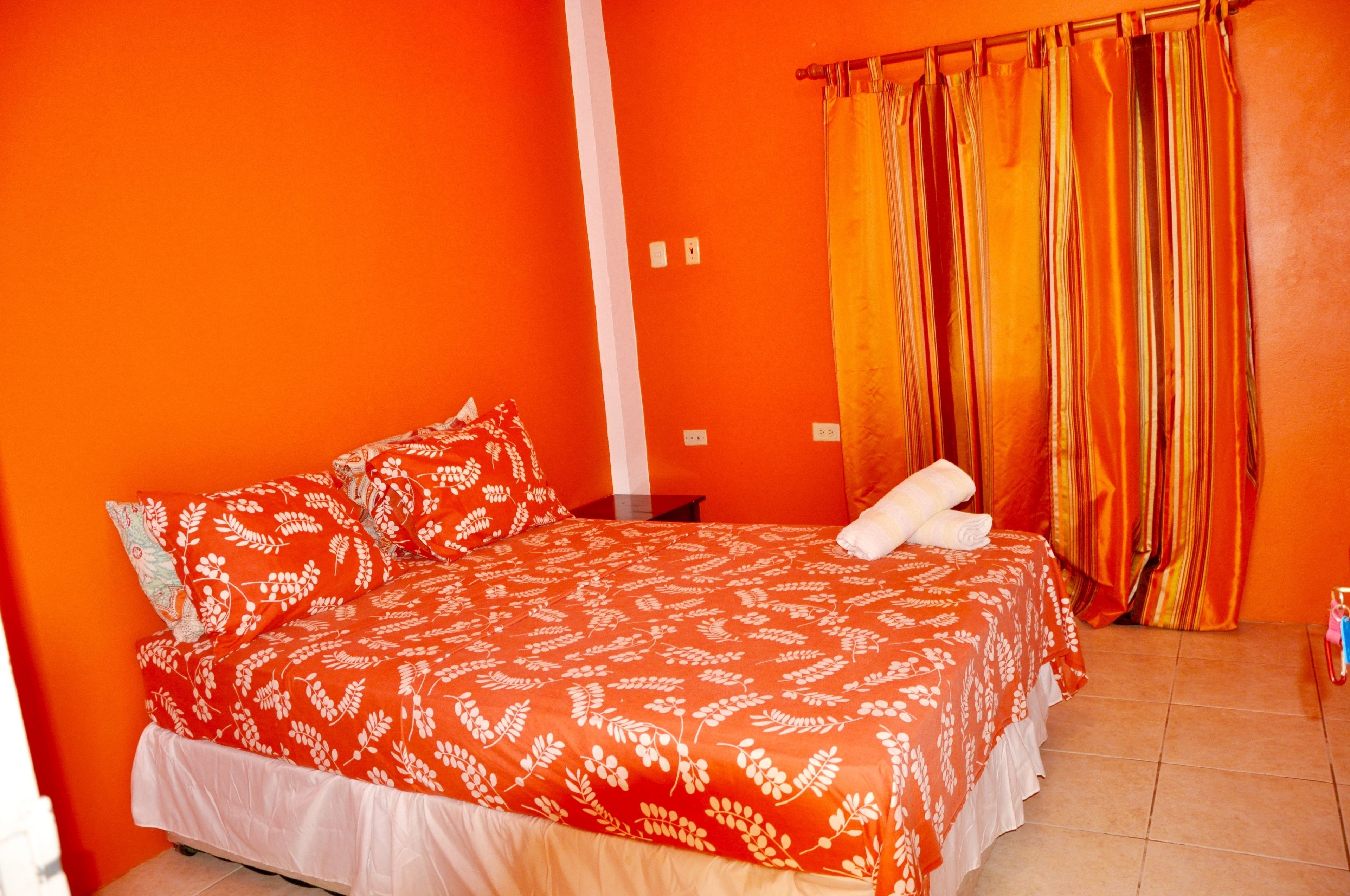 A room with a bed, a nightstand, and a window with curtains.