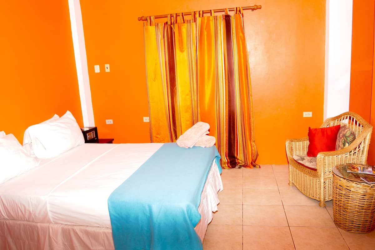 A hotel room with a bed, a chair, and a small table.