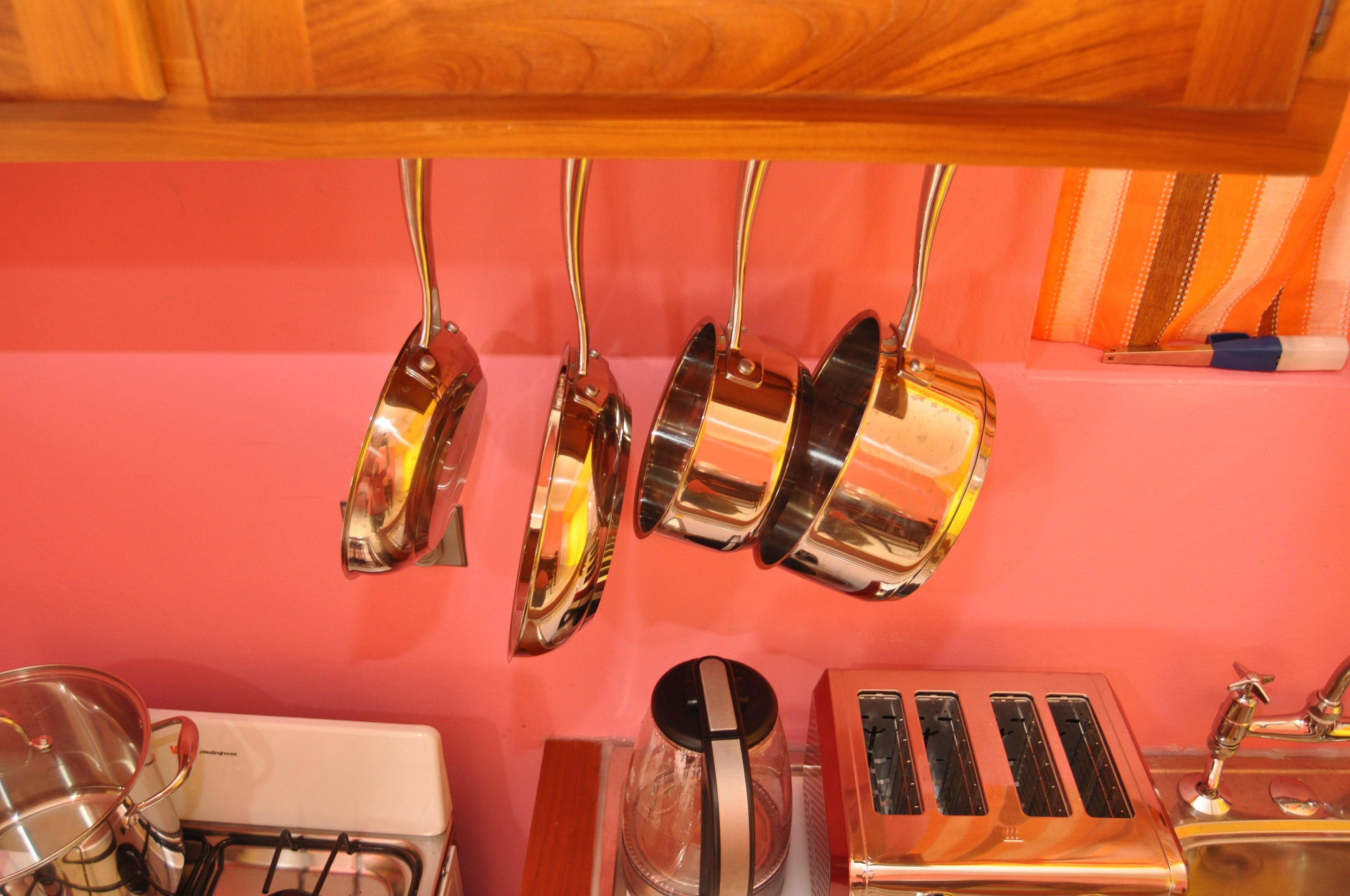 A kitchen with a gas stove, a toaster, and hanging pots.