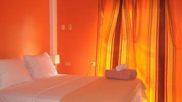 Een hotelkamer met een bed, gordijnen en een airconditioner.