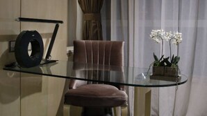 Une pièce moderne avec une table en verre, un fauteuil en cuir marron, une petite plante et un rideau.