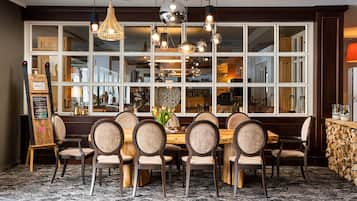 Een restaurant met een groot raam, houten stoelen, een houten tafel en hangende吊灯.