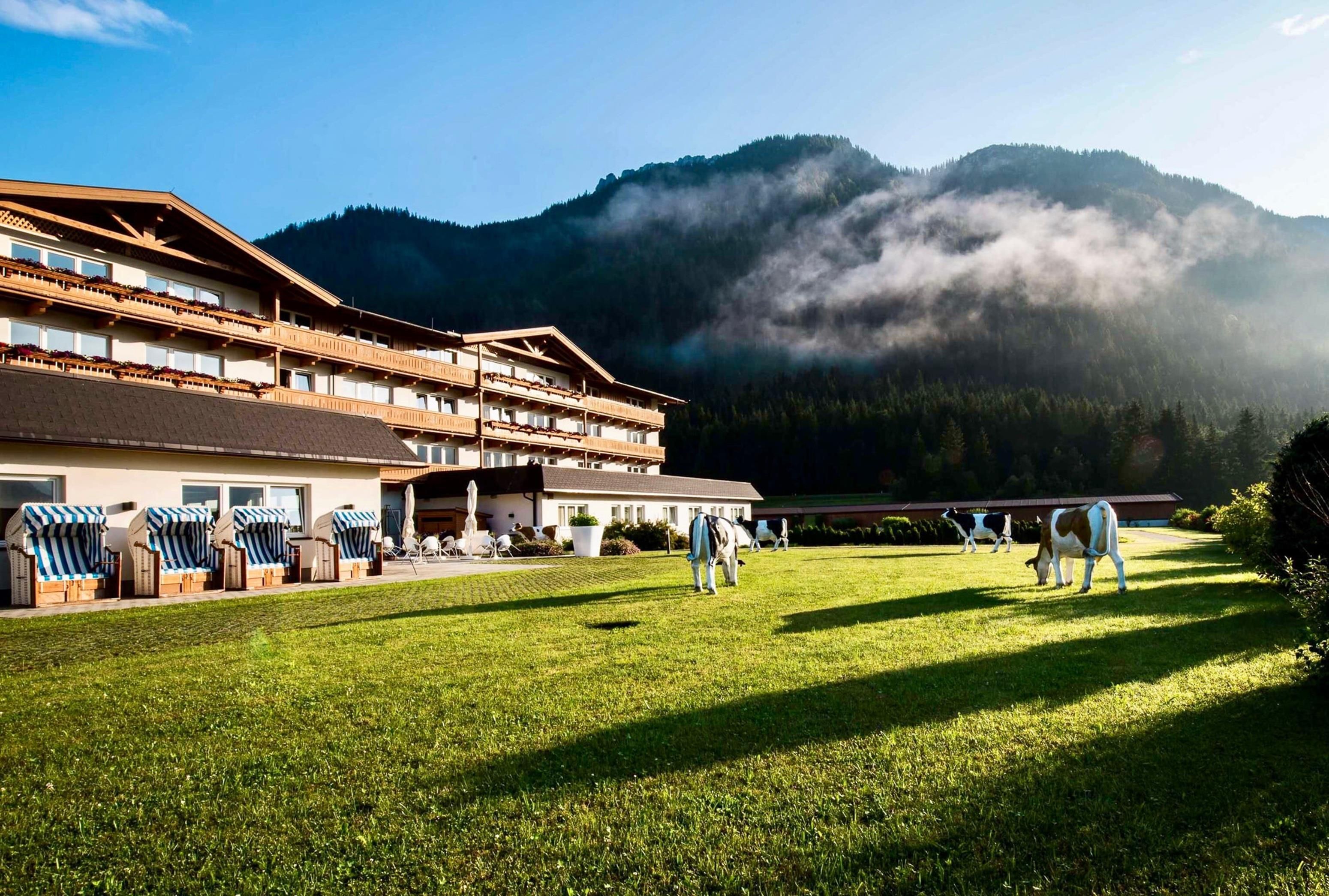 Un hotel con un edificio grande, zona de estar al aire libre y vistas a las montañas.