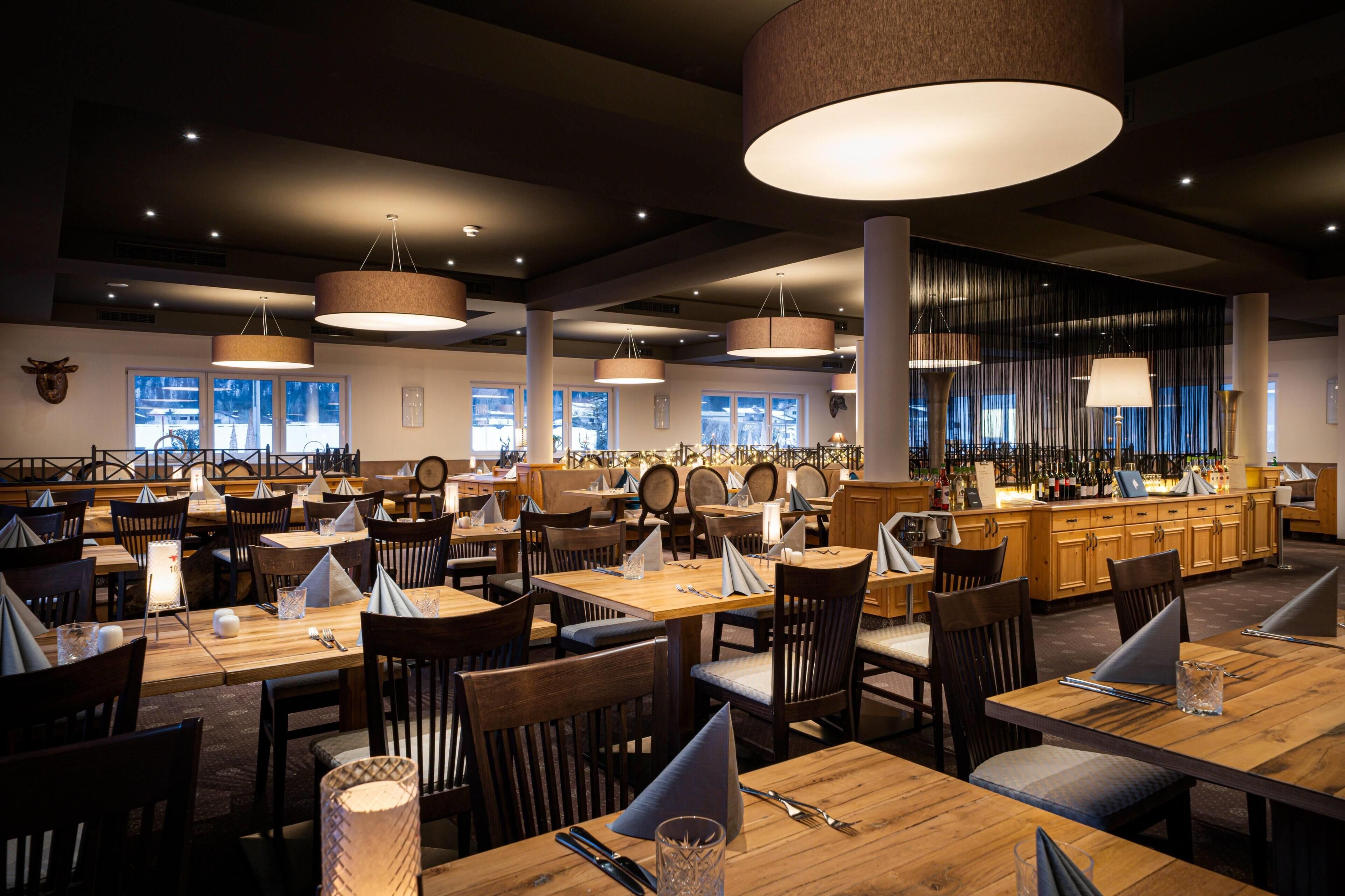 Un restaurante con varias mesas, sillas e iluminación colgante.