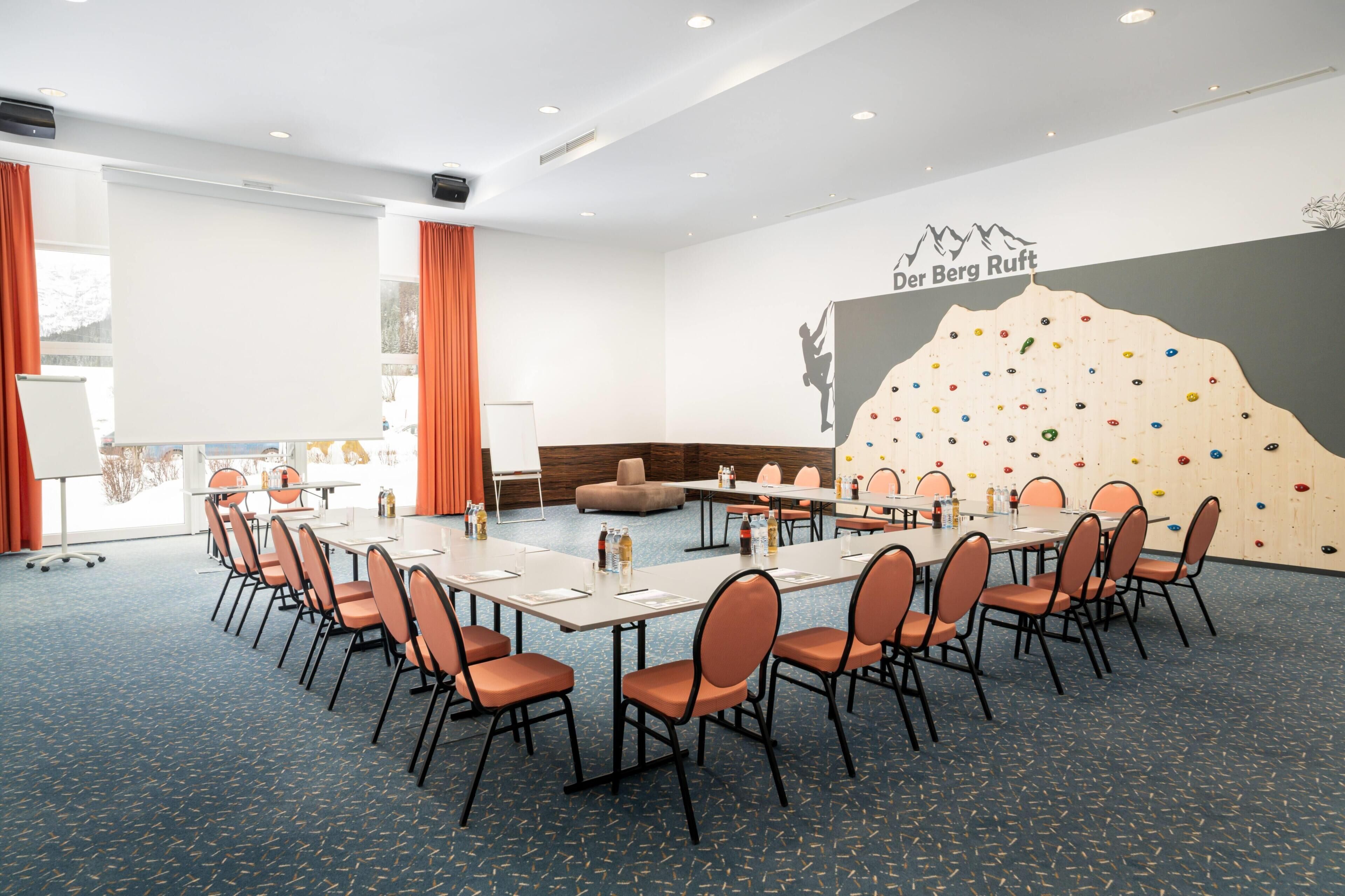 Una sala de conferencias con un mural de una pared de escalar, un sofá y una pizarra.