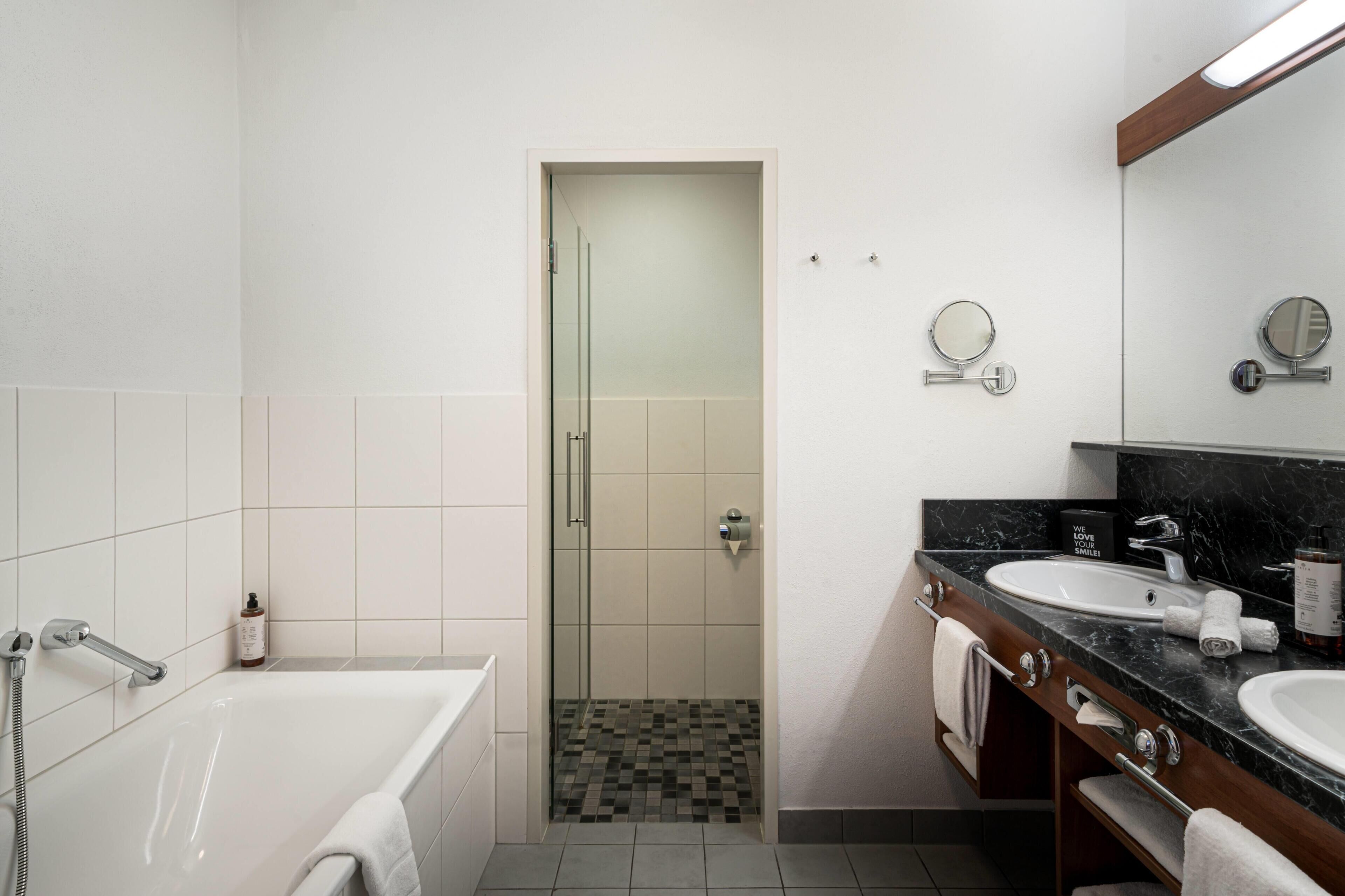 Un bagno moderno con vasca, un mobile lavabo con specchio e zona doccia.