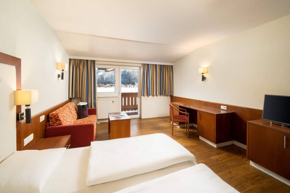 Une chambre d’hôtel équipée d’un lit, d’un bureau, d’une chaise, d’un canapé et d’une télévision.