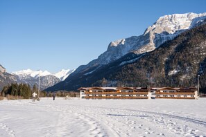 A snow-covered landscape with a building featuring multiple balconies and a mountain backdrop. - KUHOTEL Steinplatte, Trademark Collection by Wyndham (Waidring)