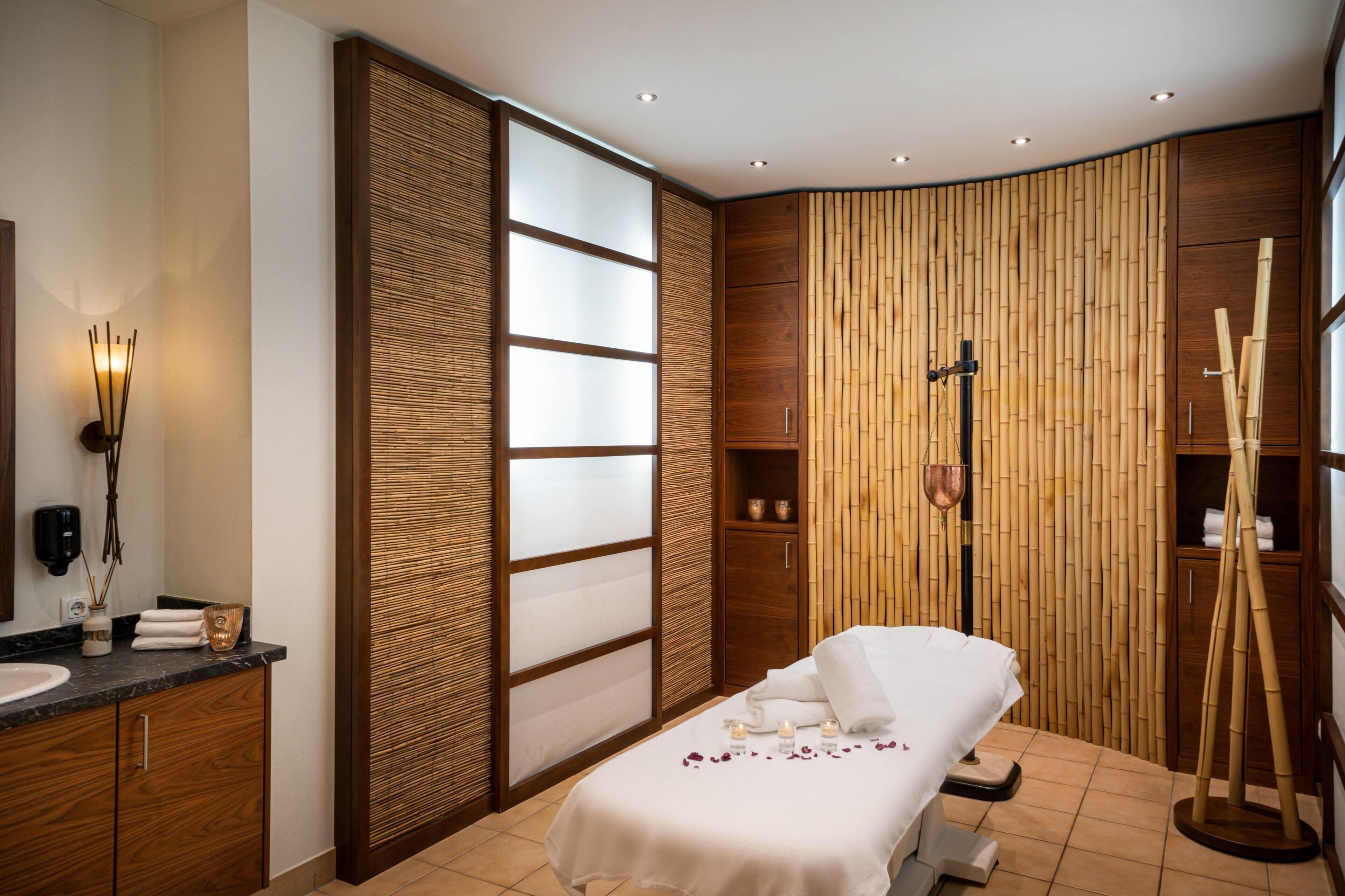 Une salle de spa comprenant un lit, une armoire en bois, une étagère murale et un mur en bambou.