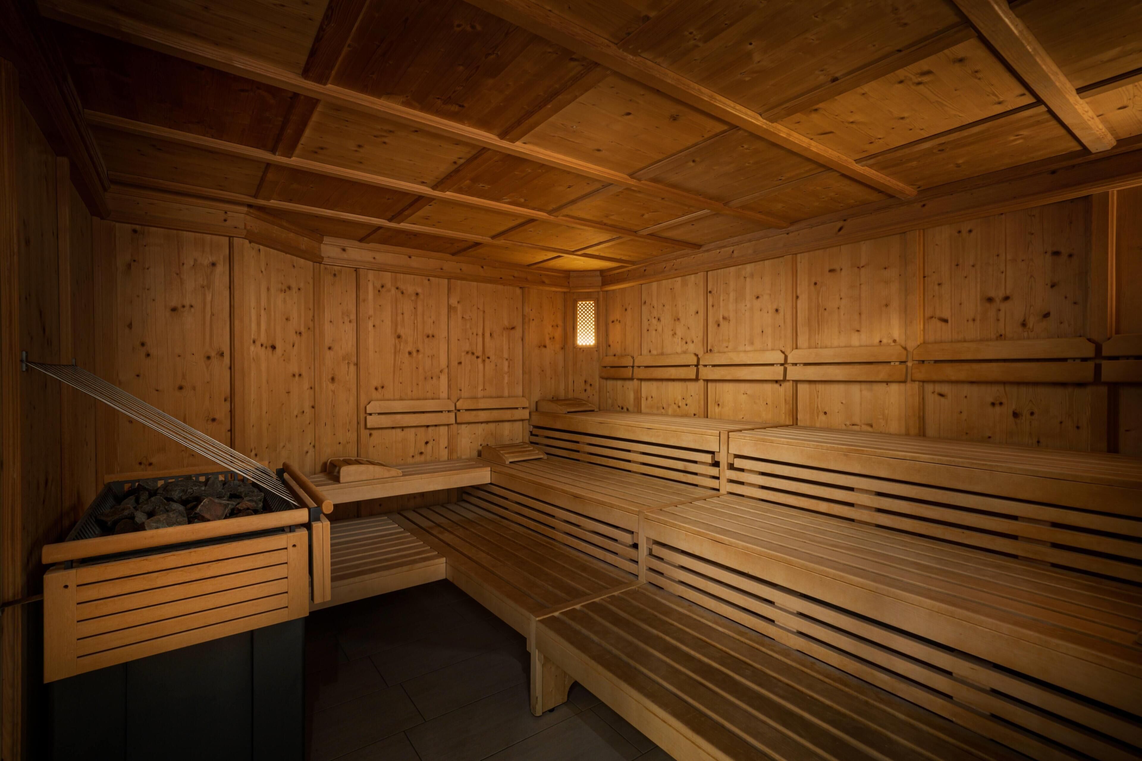 A sauna with wooden benches and a firebox.