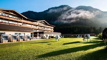 A hotel with a large building, outdoor seating area, and a view of mountains.