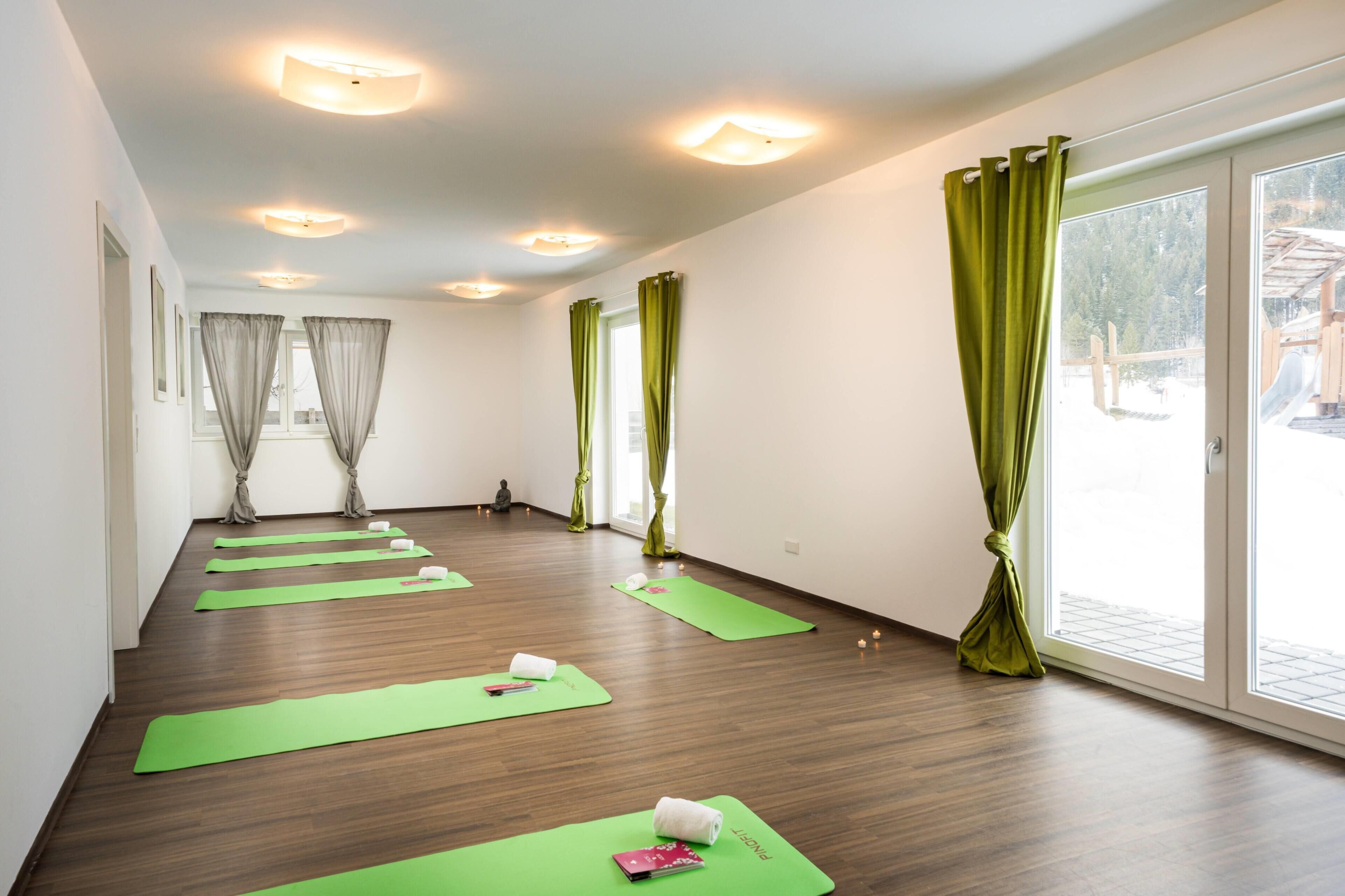 A yoga room with wooden flooring, yoga mats, and a Buddha statue.