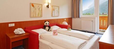 A hotel room with two beds, a red sofa, a panda plush toy, a lamp, and artwork on the wall.