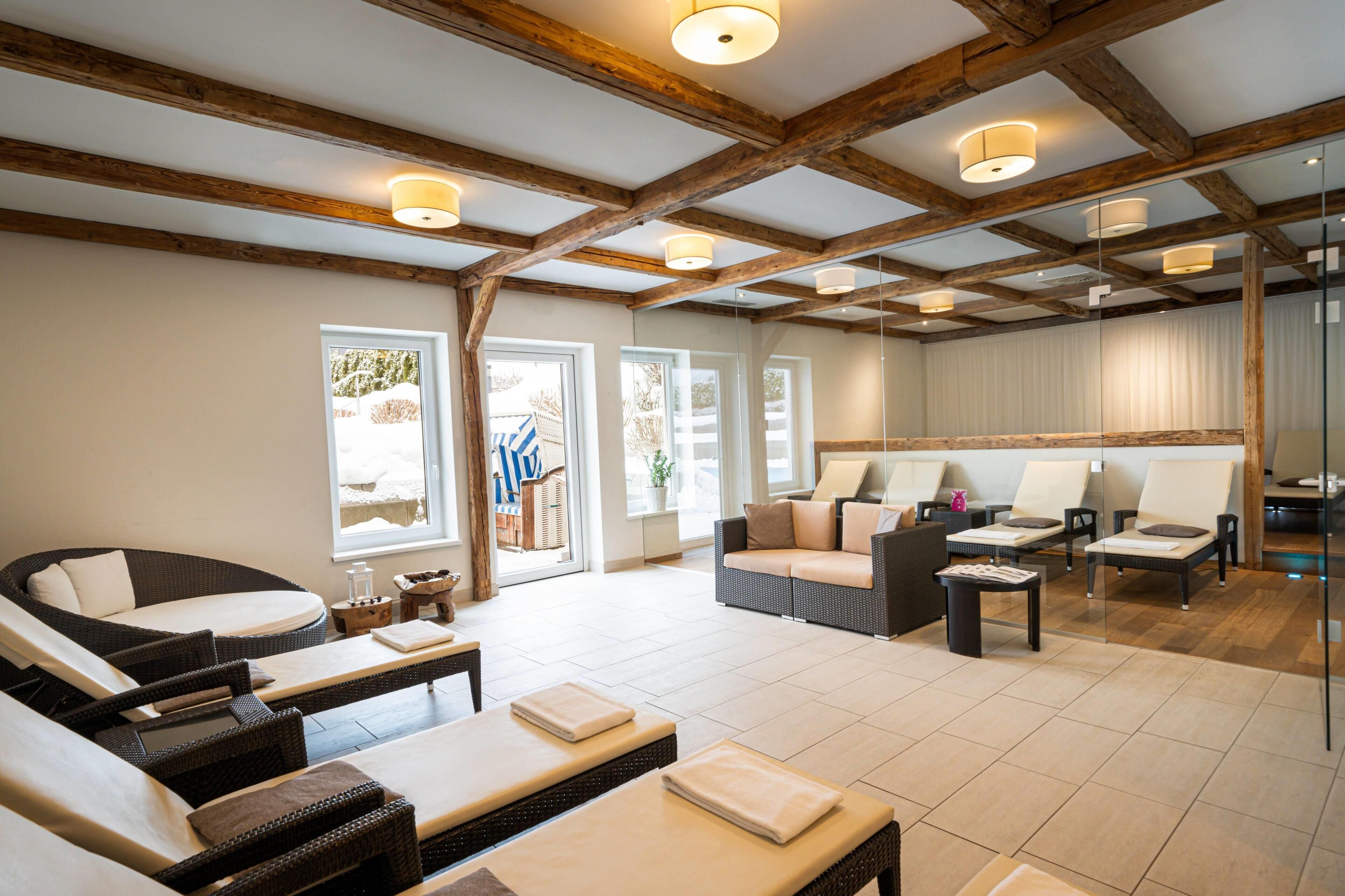 A spa room with wicker furniture, a massage table, and a glass partition.