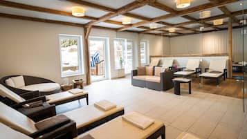 A spa room with wicker furniture, a massage table, and a glass partition.