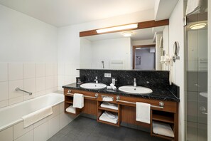 Une salle de bain moderne avec deux lavabos, une baignoire et une douche à l’italienne.