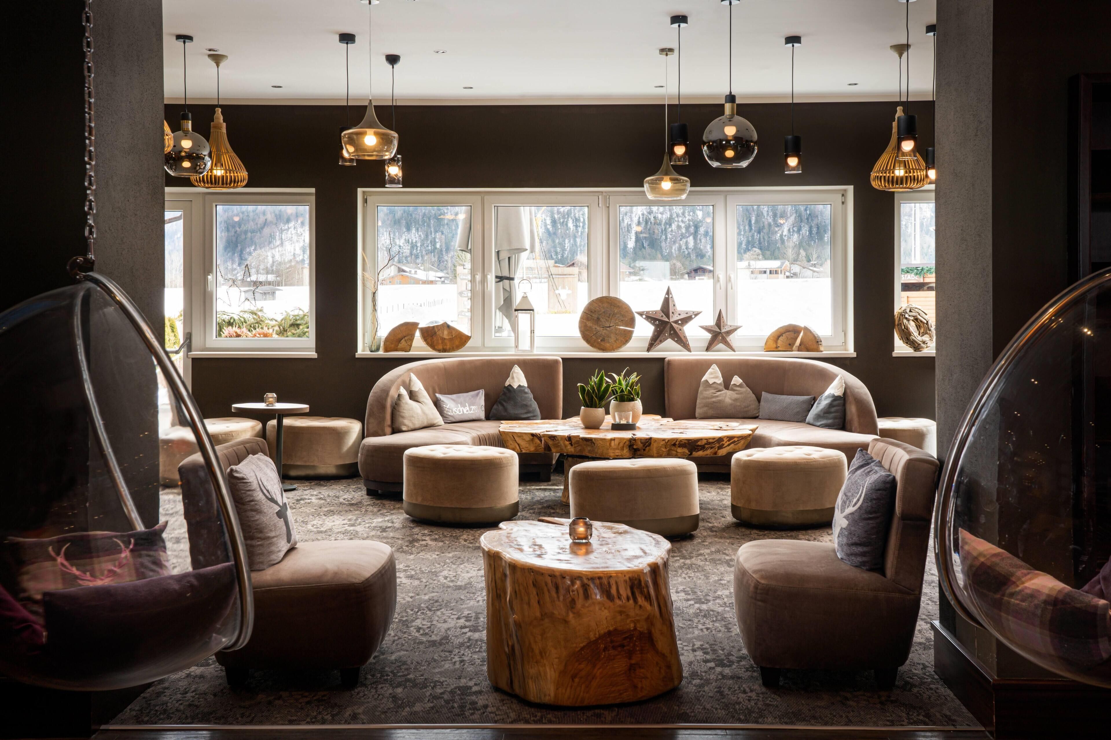 A modern lounge area with sofas, ottomans, and hanging light fixtures.