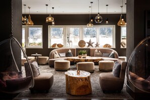 A modern lounge area with sofas, ottomans, and hanging light fixtures. - KUHOTEL Steinplatte, Trademark Collection by Wyndham (Waidring)