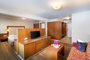 A hotel room with a bed, a TV on a wooden dresser, a desk, and a wardrobe. - KUHOTEL Steinplatte, Trademark Collection by Wyndham (Waidring)