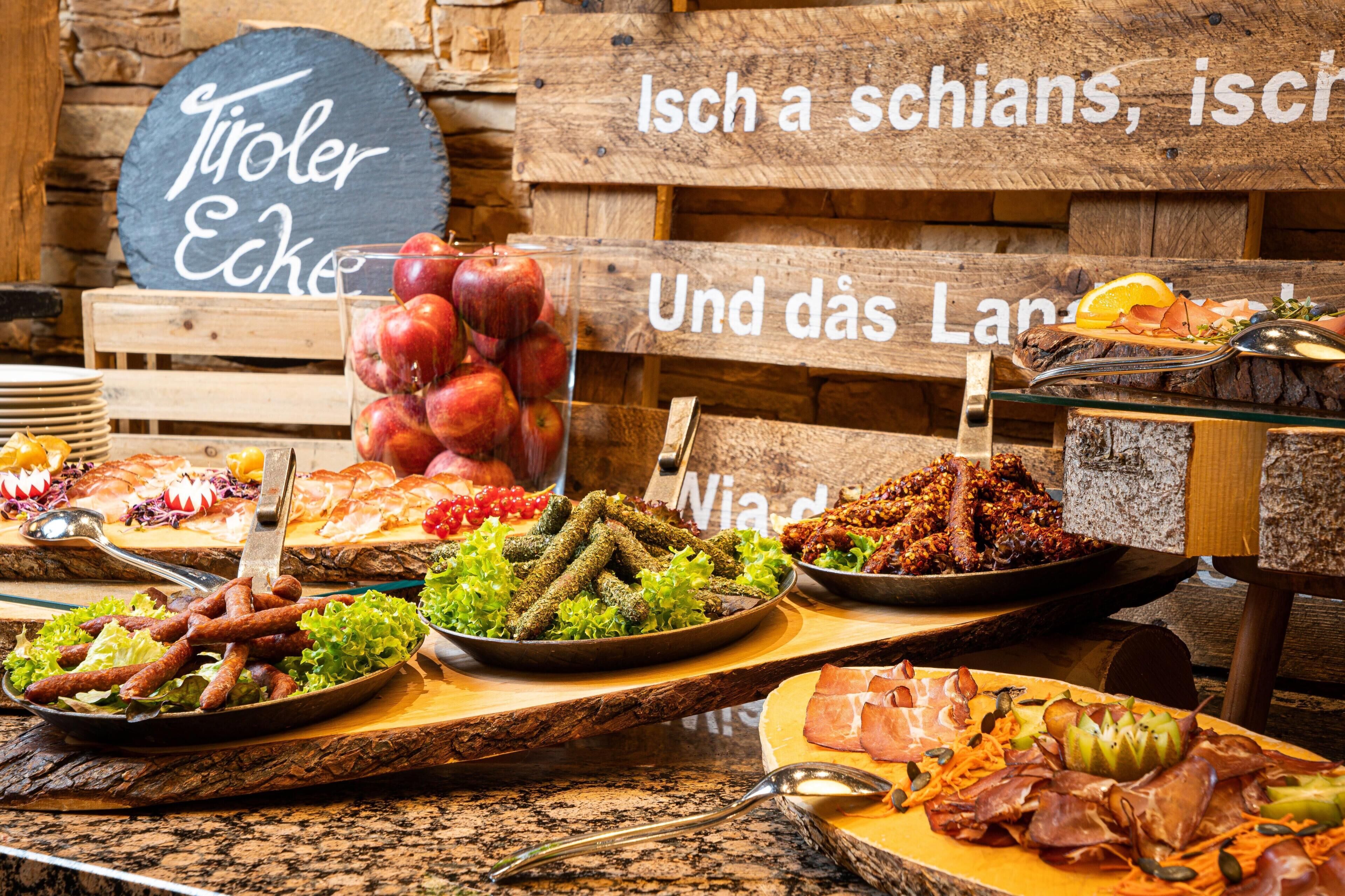 A buffet with various dishes including meats, cheeses, and fruits.