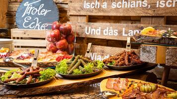 A buffet with various dishes including meats, cheeses, and fruits.