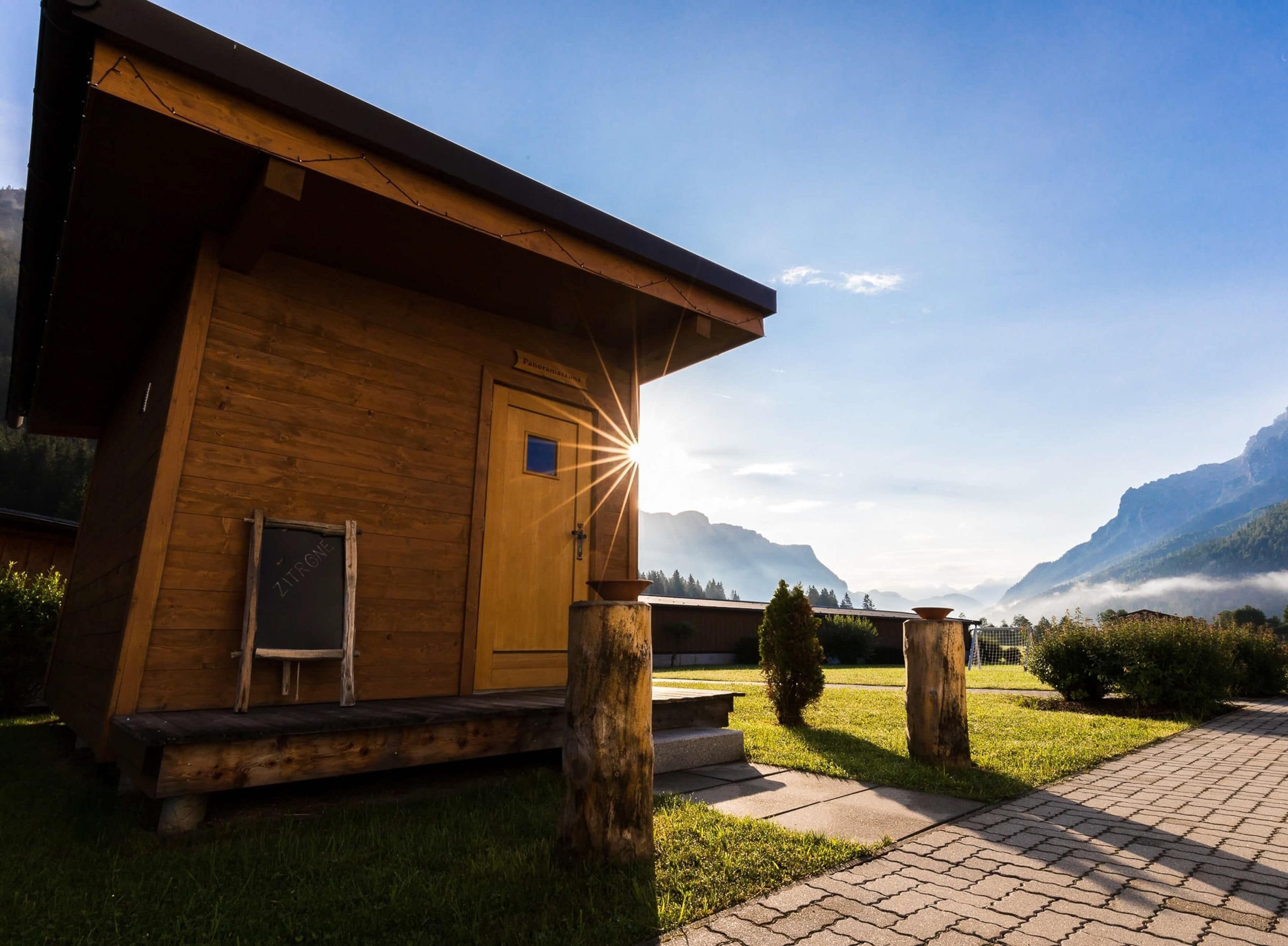 A wooden cabin with a door, a window, and a view of mountains in the background.